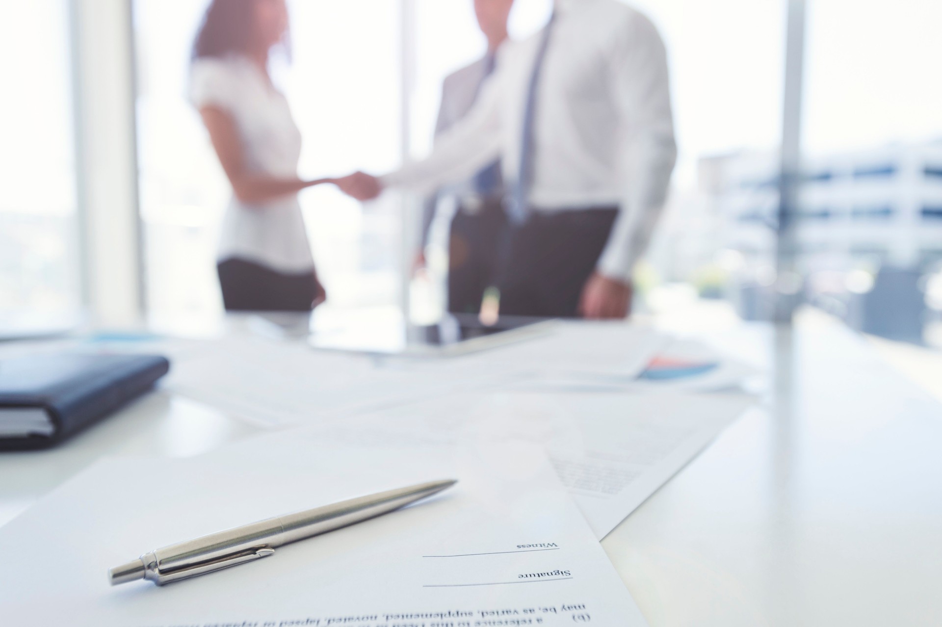 Business woman and business man shaking hands with a contract.